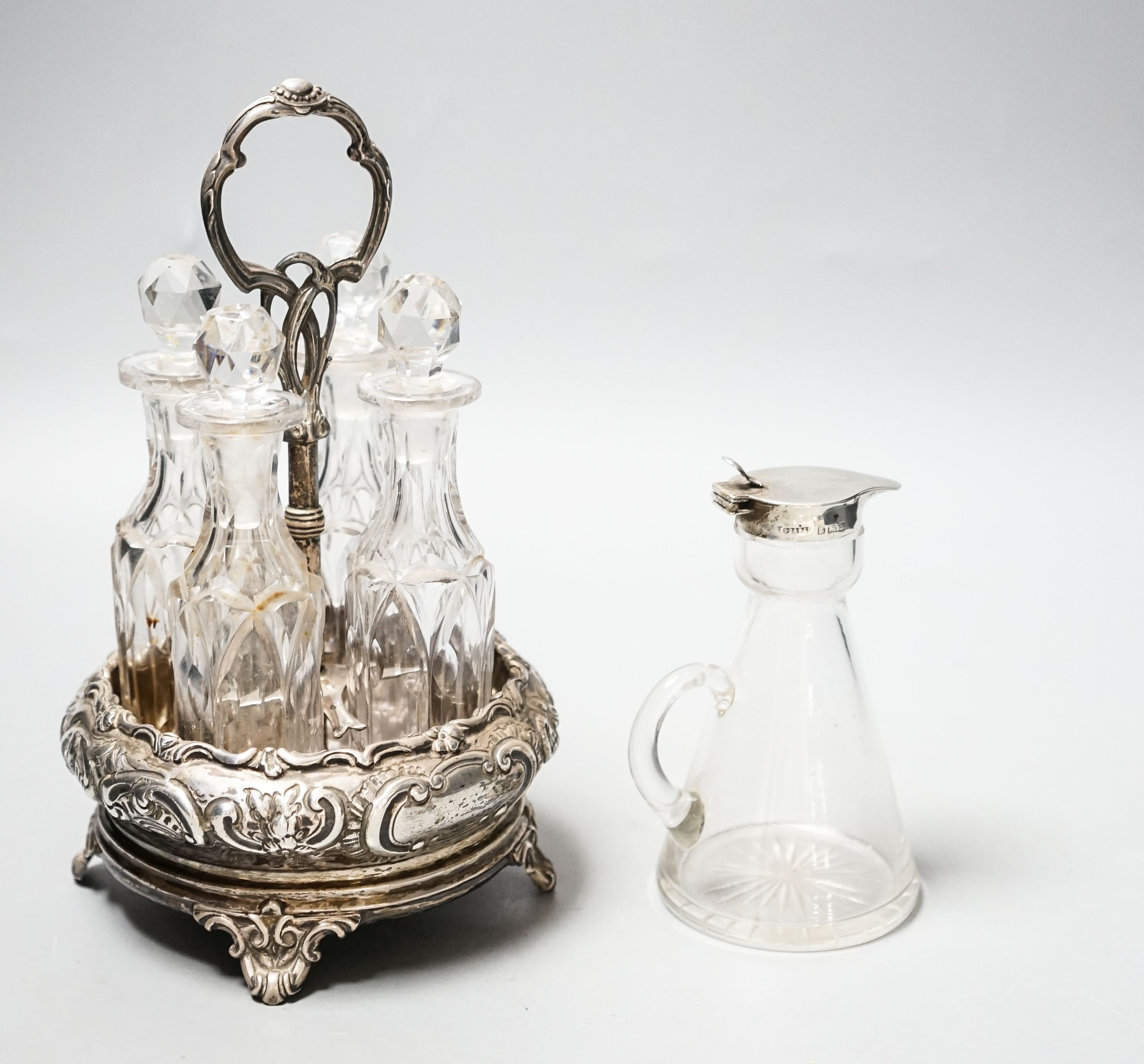 A late Victorian silver circular four division cruet stand, William Evans, London, 1884, height 20.5cm, with four glass bottles, together with a George V silver mounted glass whisky tot jug, Birmingham, 1923.